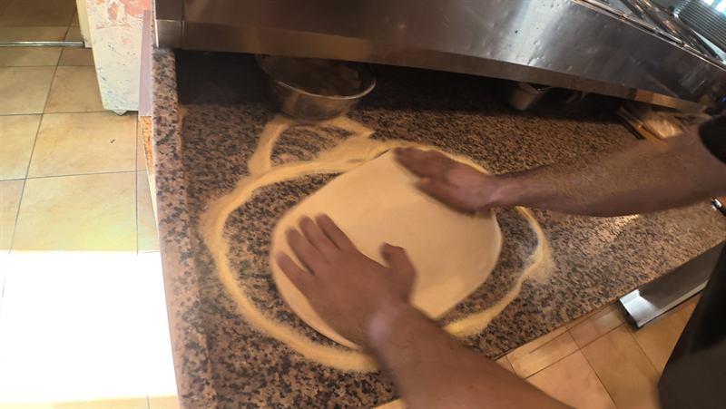 Pizzateig wird von Hand auf dem Granit ausgezogen