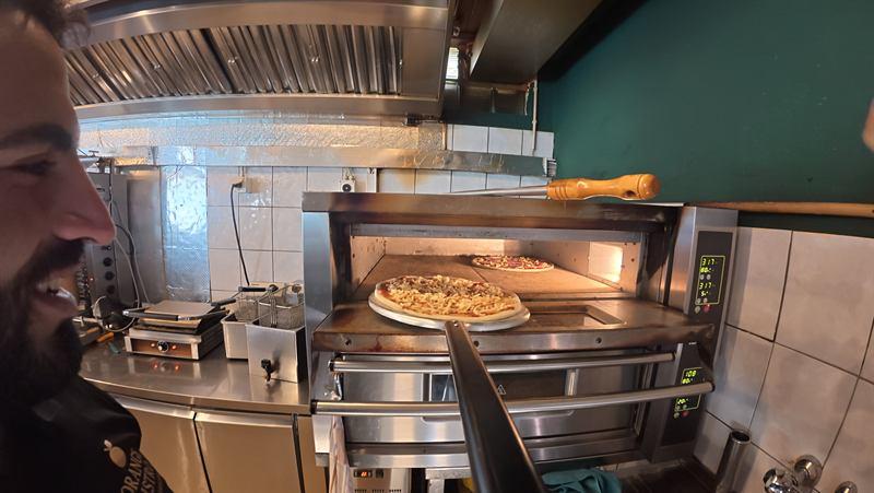Pizza wird in den Steinofen geschoben