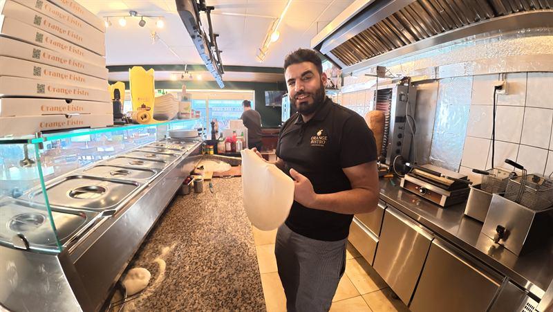 Der von Hand ausgezogene Teigfladen wird hochgehalten